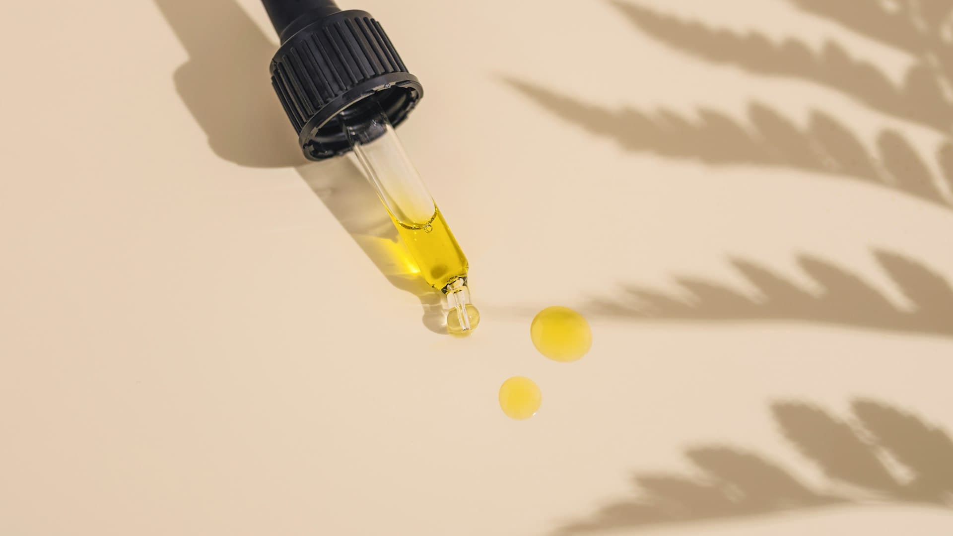 Botol serum dengan pipet berisi cairan kuning keemasan diletakkan di atas meja