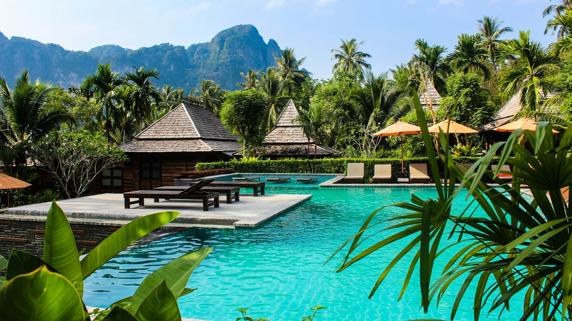 Bangku kayu cokelat di tepi kolam renang spa yang sunyi dan teduh