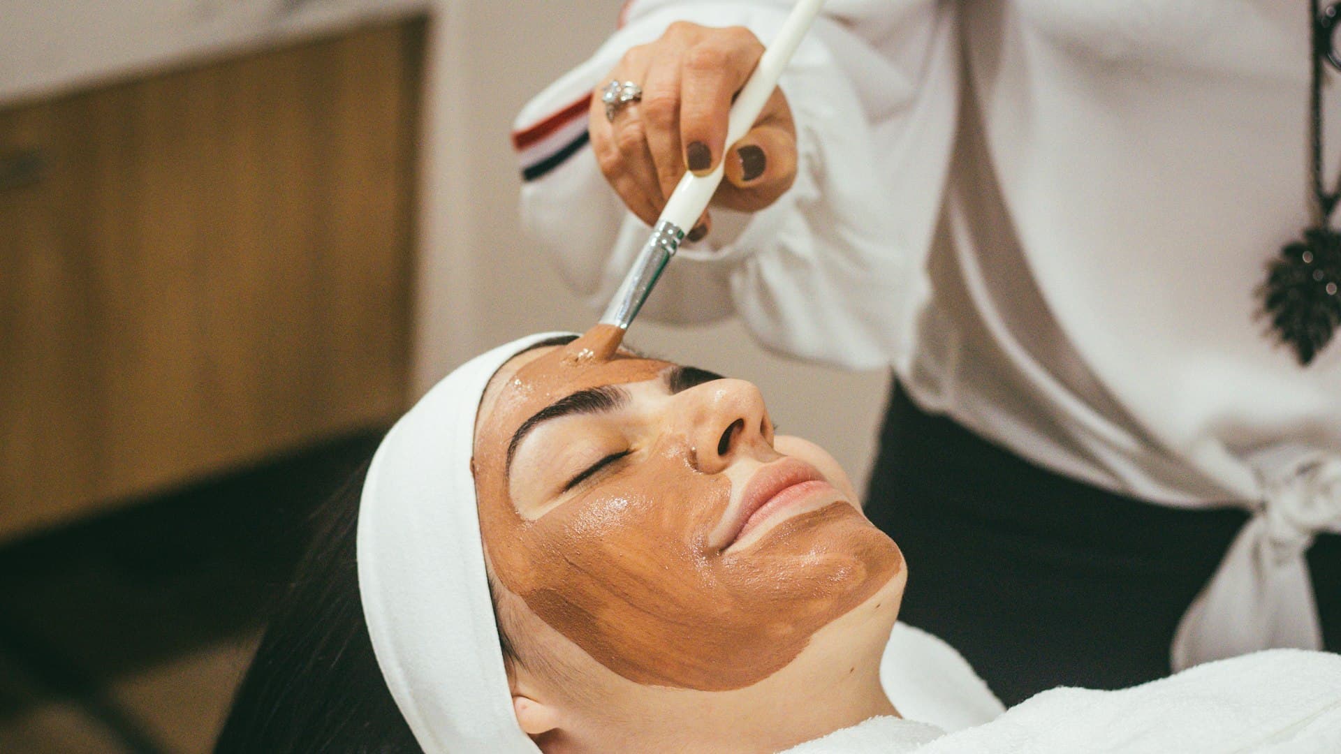 Seorang perempuan menerima perawatan masker wajah yang menenangkan di ruang spa