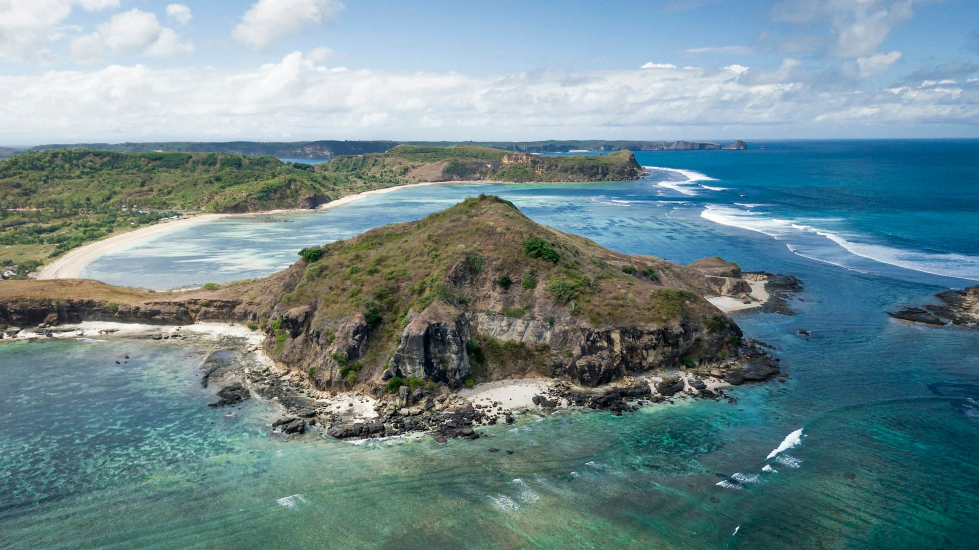 Pulau kecil di tengah laut tenang dengan daratan Lombok di kejauhan