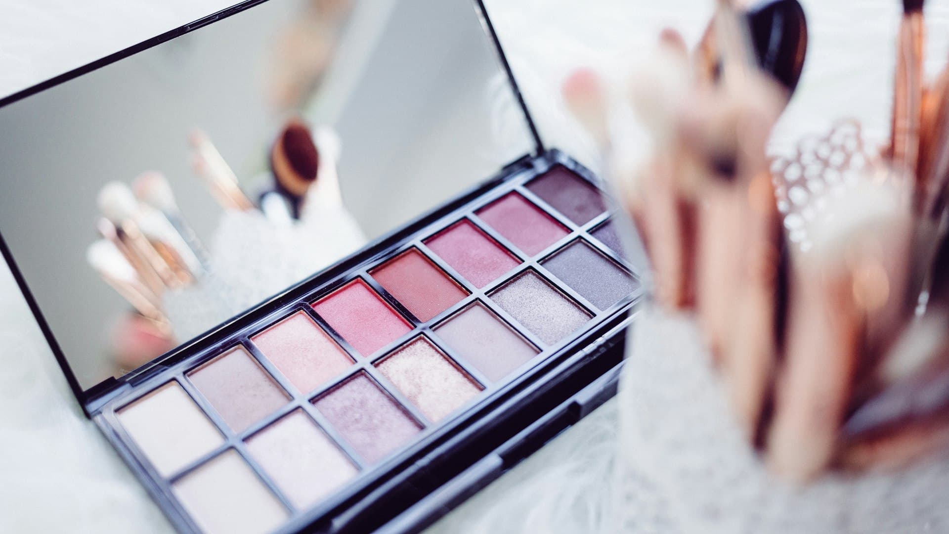 Palet eyeshadow dan kuas rias tertata di meja, menunggu diuji sebelum dibeli