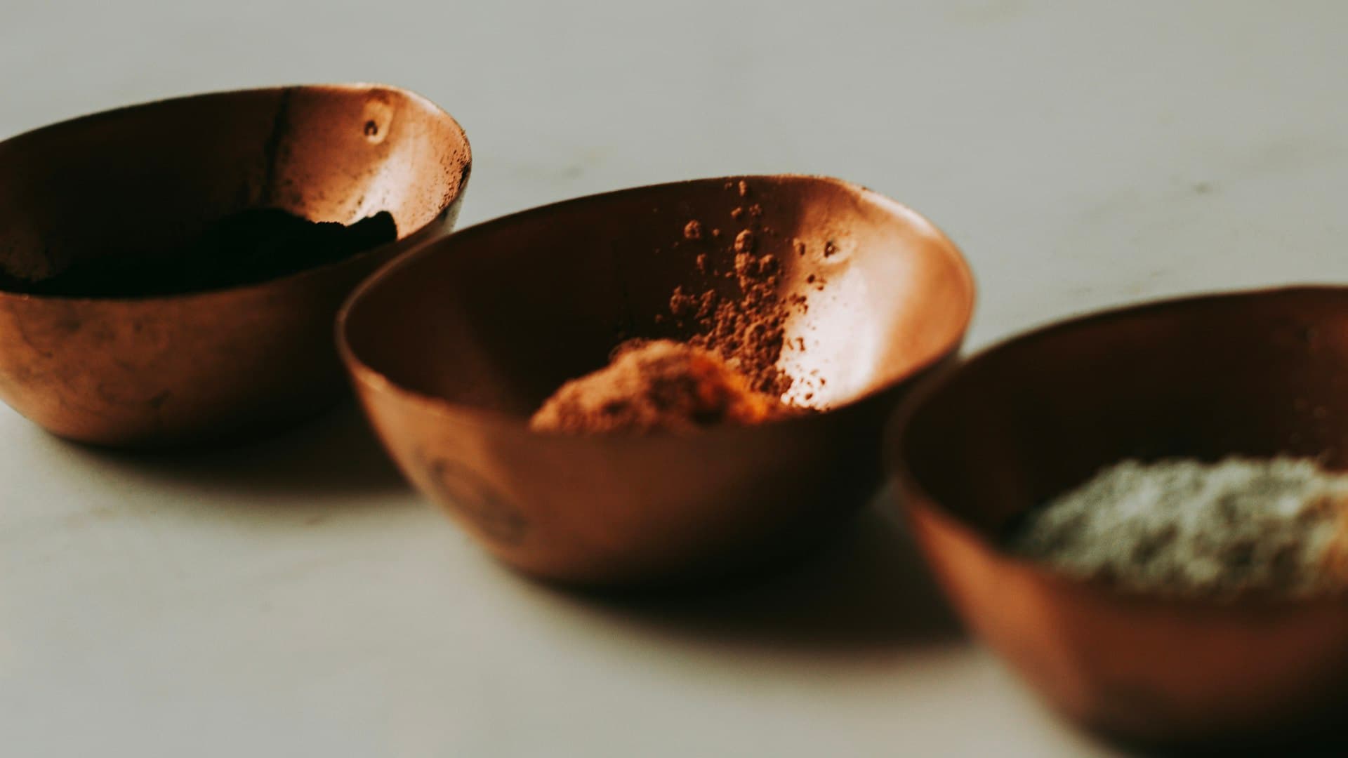 Mangkuk-mangkuk keramik cokelat dan hitam berisi bahan ramuan tradisional ayurveda