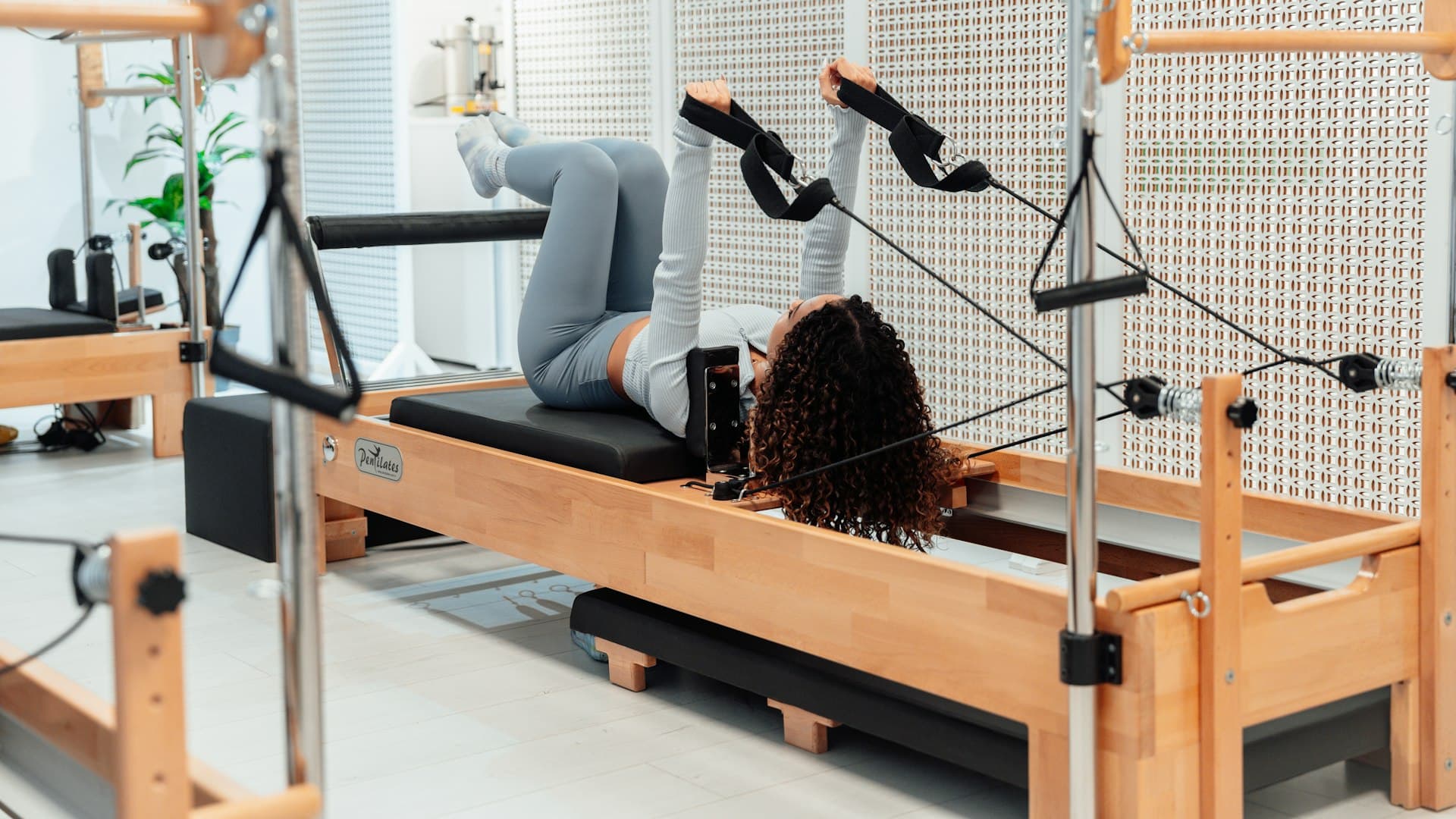 Perempuan berlatih dengan mesin reformer di studio, gerakan terkontrol khas pilates