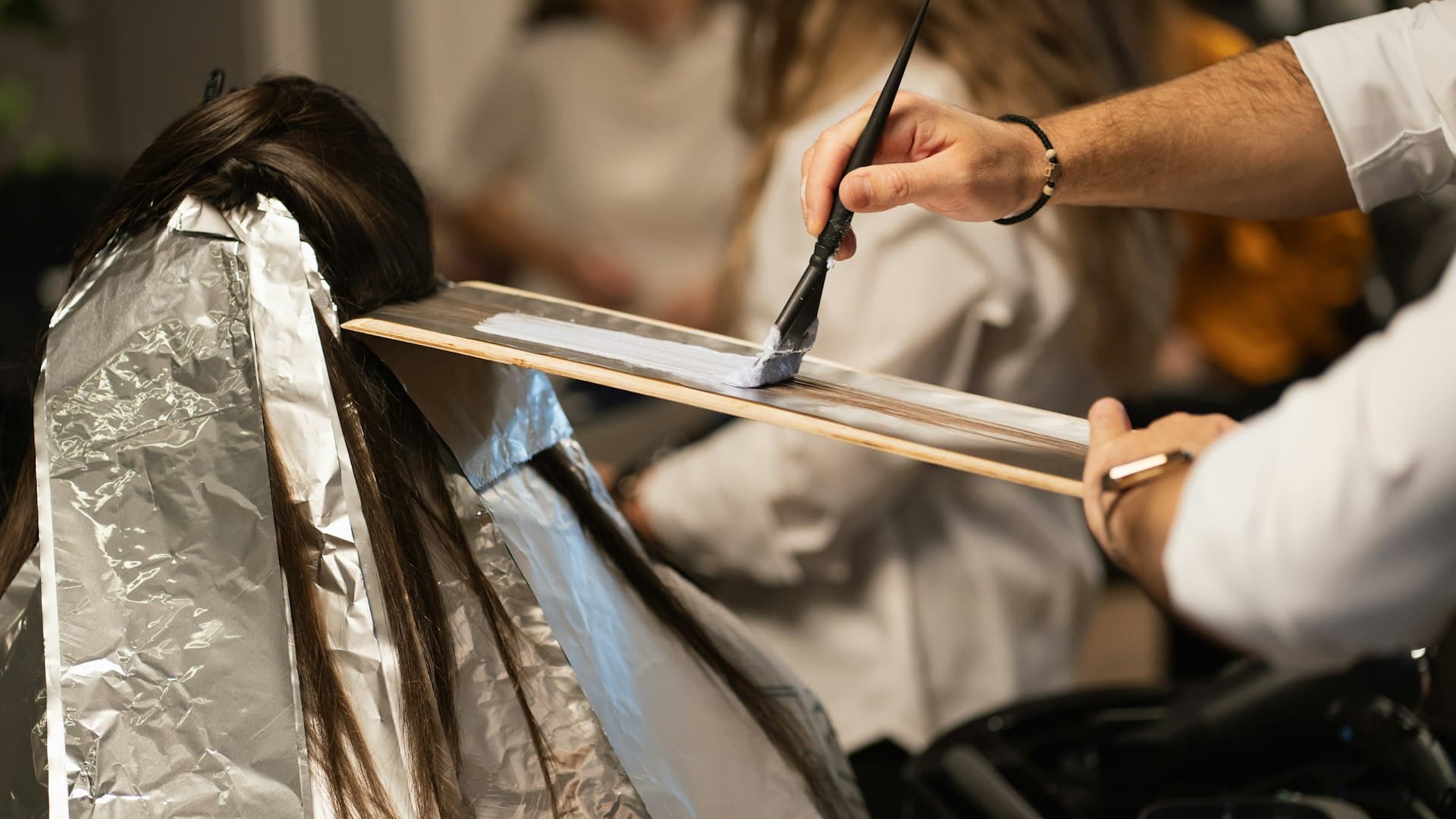 Seorang penata rambut menggunting rambut klien perempuan di salon dengan penuh ketelitian