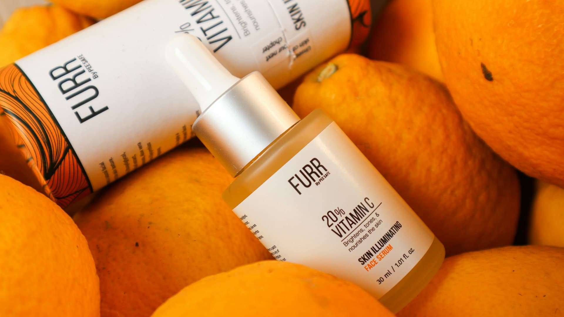 Tumpukan buah jeruk segar di samping tabung serum vitamin C berwarna cerah