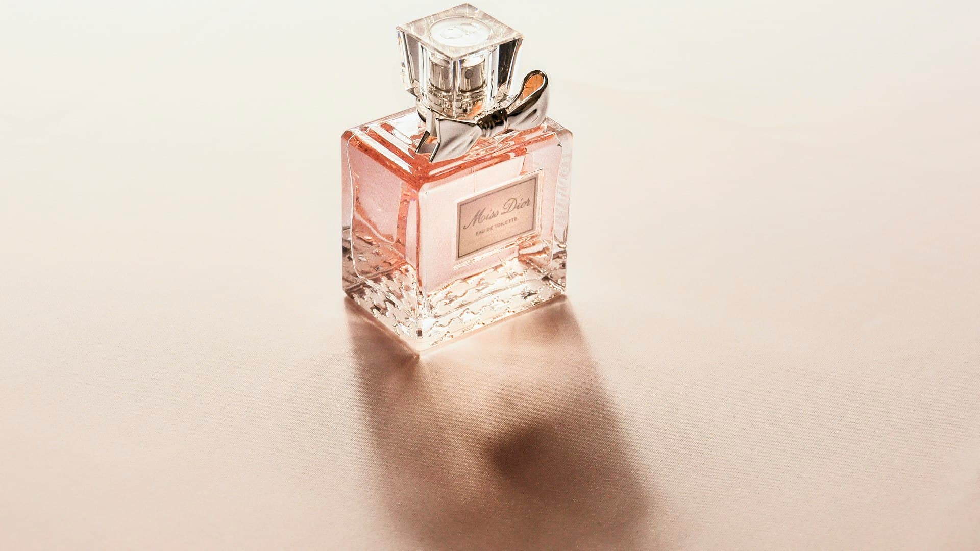 Botol parfum kaca bening yang elegan berdiri sederhana dengan cahaya lembut menerpanya