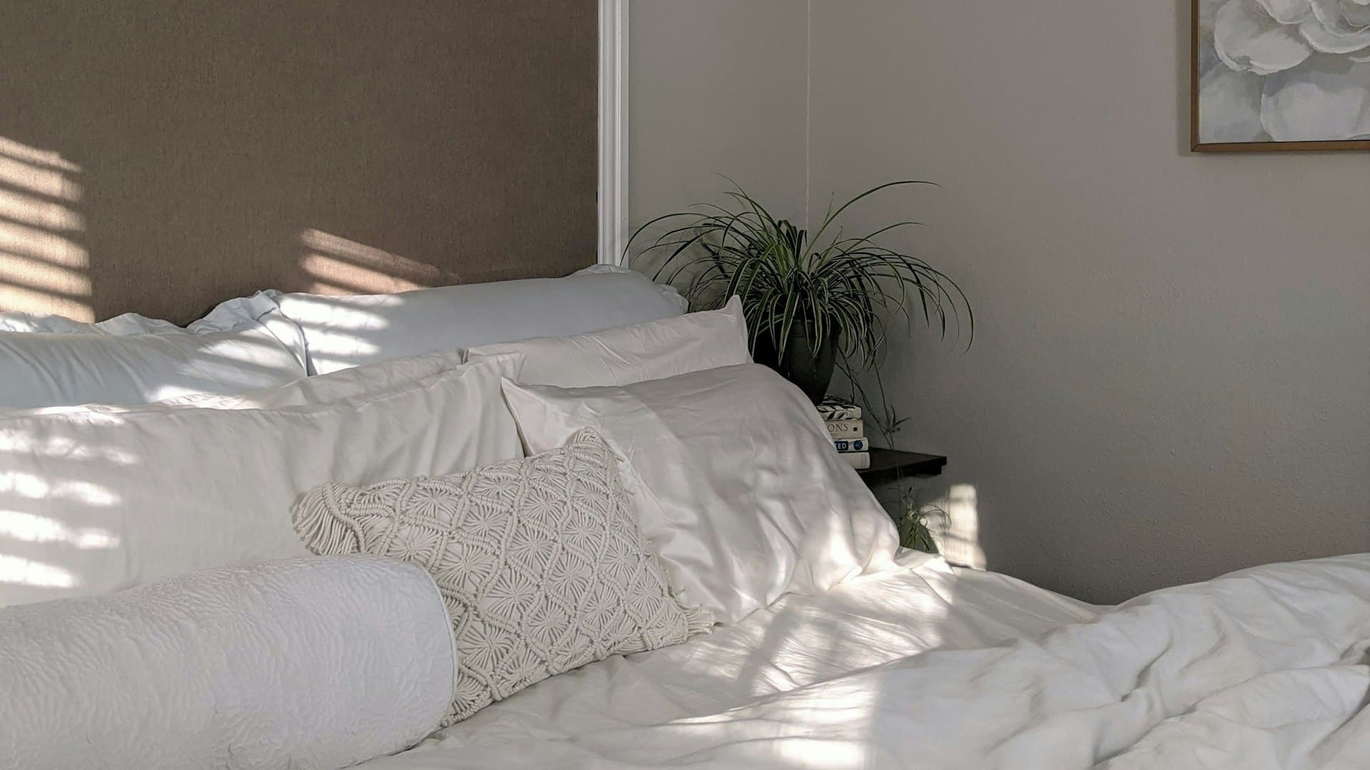 Linen tempat tidur putih bersih bersanding dengan tanaman hijau di kamar tropis