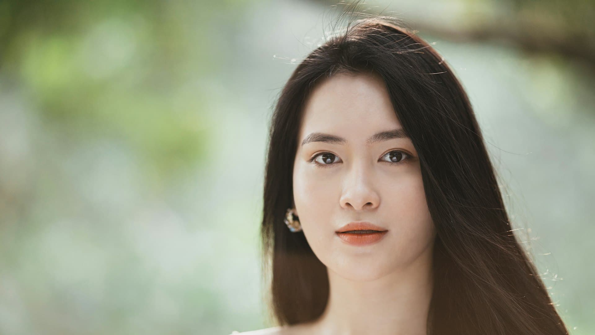 Perempuan mengenakan tank top putih dengan rambut tergerai, potret kesegaran di iklim tropis