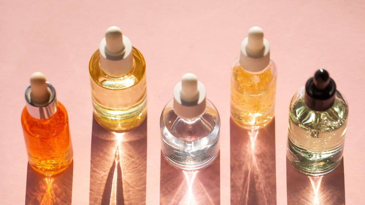 Botol serum perawatan kulit dengan pipet di atas permukaan berwarna merah muda lembut